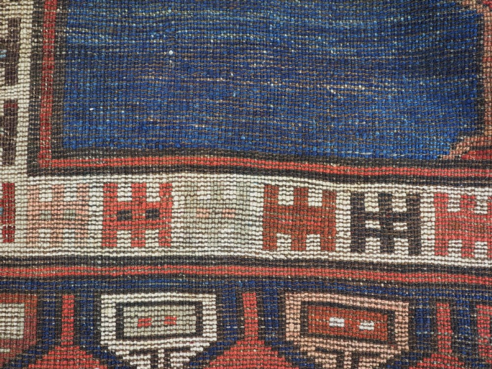 An antique 19th-century Turkish Karapinar wool rug featuring a central geometric medallion in blue, green, and cream set against a deep red ground field with multi-coloured geometric borders. View XIV