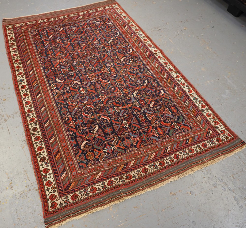 An antique hand-knotted wool Afshar rug featuring an all-over geometric Herati design on a dark navy blue field with a patterned cream border. View II