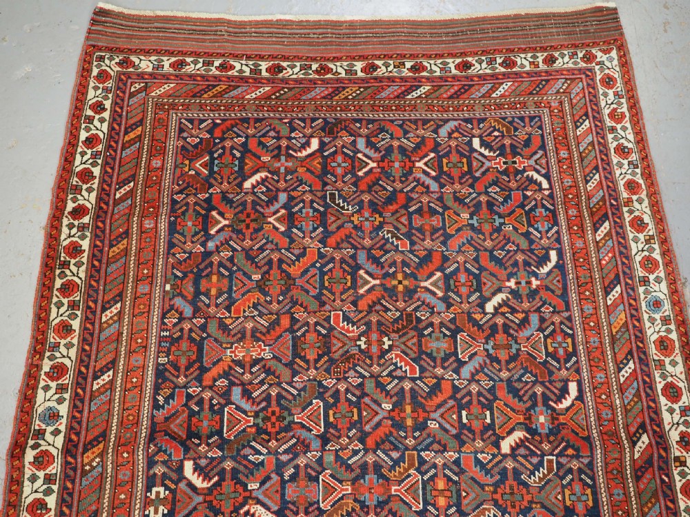An antique hand-knotted wool Afshar rug featuring an all-over geometric Herati design on a dark navy blue field with a patterned cream border. View III
