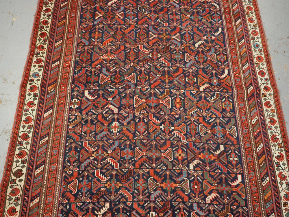 An antique hand-knotted wool Afshar rug featuring an all-over geometric Herati design on a dark navy blue field with a patterned cream border. View IV