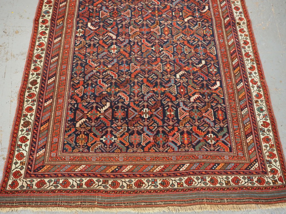 An antique hand-knotted wool Afshar rug featuring an all-over geometric Herati design on a dark navy blue field with a patterned cream border. View V