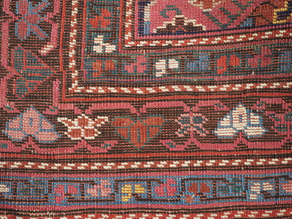An antique long Caucasian runner rug featuring repeating pink and yellow geometric medallions on a dark navy field surrounded by a multi-band decorative border. View XIV