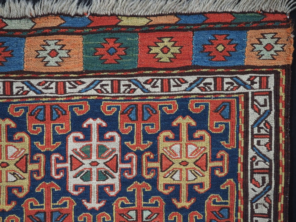 An antique square Shahsavan wool bag face featuring geometric tribal motifs woven in Soumak flatweave technique with red, blue, green, and cream hues. View III