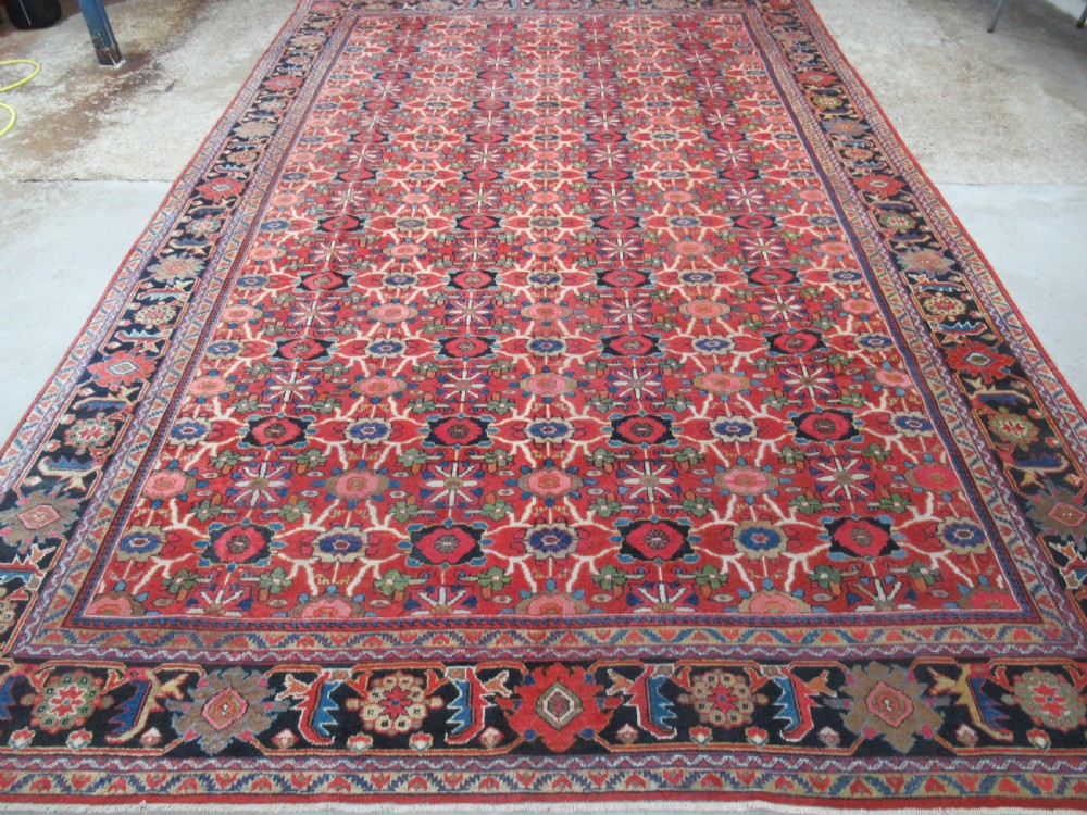A large antique Persian Mahal wool carpet featuring a red field with an all-over floral Mina Khani lattice pattern framed by a dark navy decorative border.
