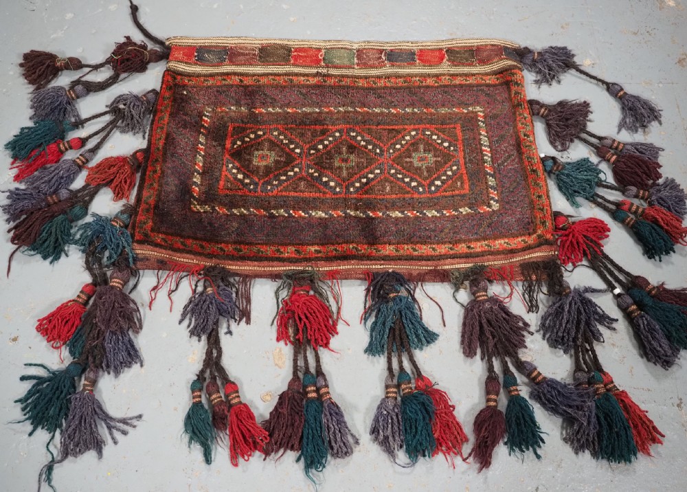 ANTIQUE AFGHAN TRIBAL STORAGE BAG COMPLETE WITH TASSELS, CIRCA 1920.