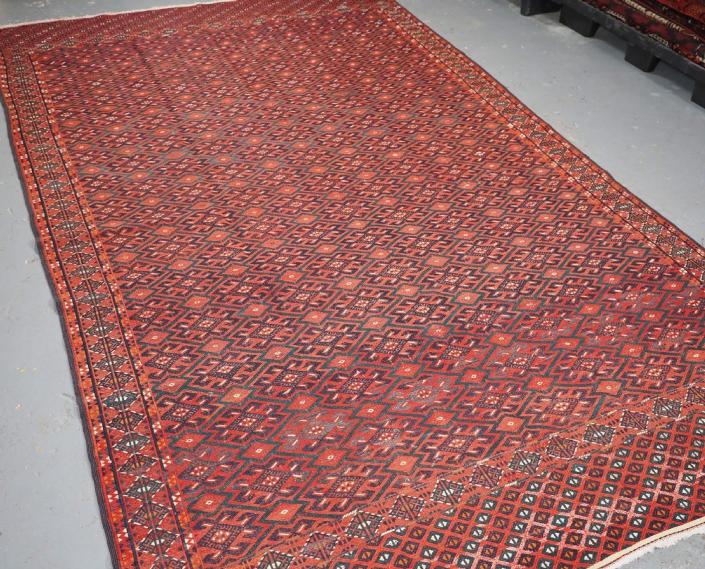 A large rectangular deep red wool flatweave carpet featuring an all-over diamond lattice pattern with detailed geometric borders and palas ends. View II