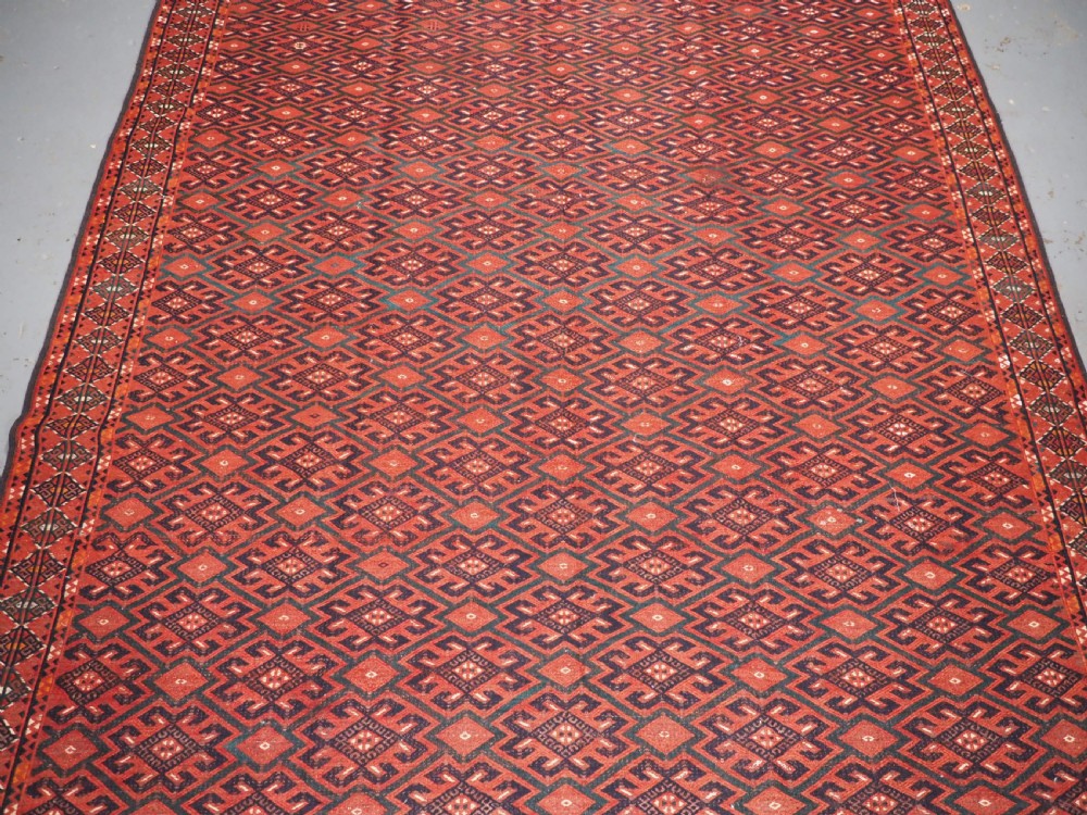 A large rectangular deep red wool flatweave carpet featuring an all-over diamond lattice pattern with detailed geometric borders and palas ends. View IV