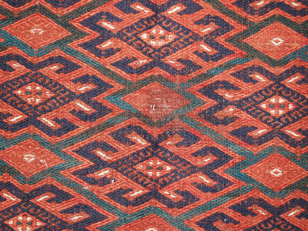 A large rectangular deep red wool flatweave carpet featuring an all-over diamond lattice pattern with detailed geometric borders and palas ends. View XI