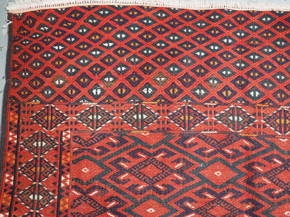 A large rectangular deep red wool flatweave carpet featuring an all-over diamond lattice pattern with detailed geometric borders and palas ends. View XIV
