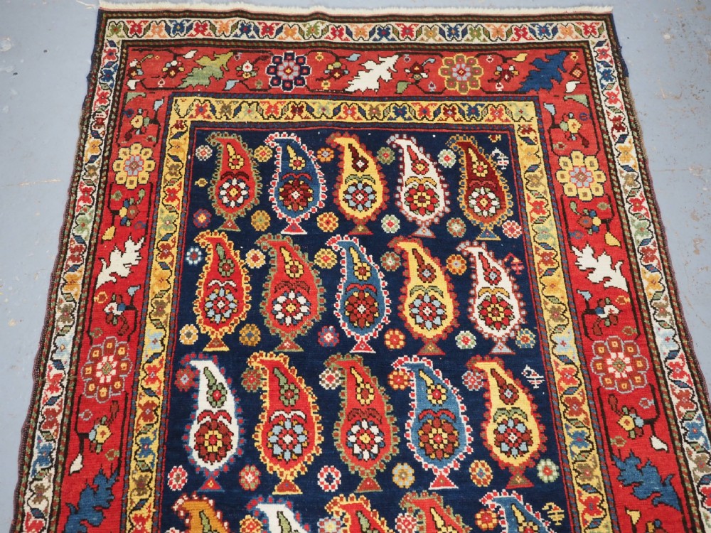 An antique Caucasian Karabagh hand-knotted wool runner rug featuring repeating multi-coloured boteh patterns on a dark navy field surrounded by a red floral border. View III