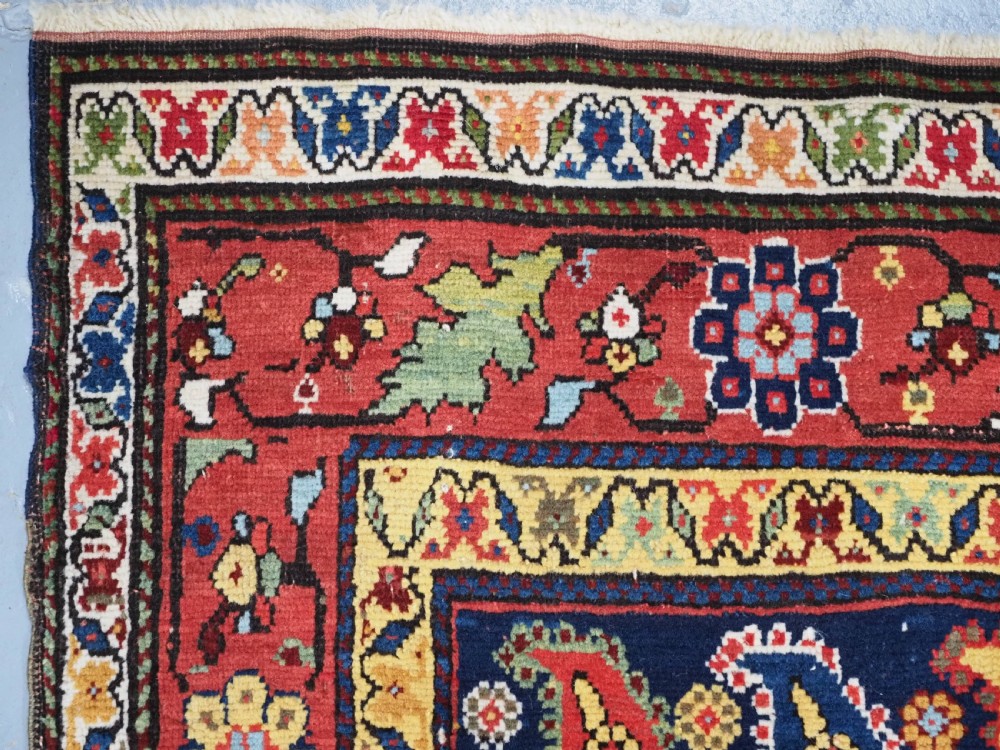 An antique Caucasian Karabagh hand-knotted wool runner rug featuring repeating multi-coloured boteh patterns on a dark navy field surrounded by a red floral border. View VII