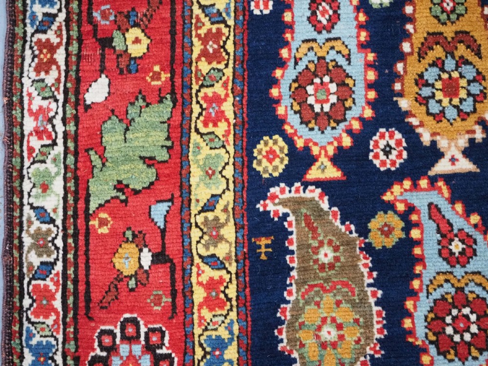 An antique Caucasian Karabagh hand-knotted wool runner rug featuring repeating multi-coloured boteh patterns on a dark navy field surrounded by a red floral border. View VIII