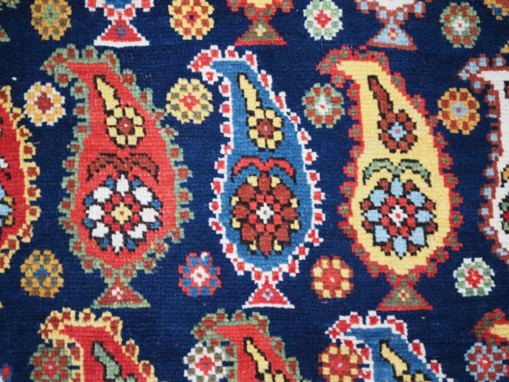 An antique Caucasian Karabagh hand-knotted wool runner rug featuring repeating multi-coloured boteh patterns on a dark navy field surrounded by a red floral border. View IX