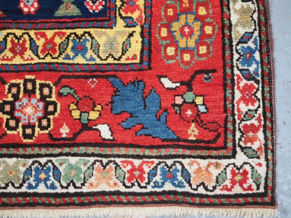 An antique Caucasian Karabagh hand-knotted wool runner rug featuring repeating multi-coloured boteh patterns on a dark navy field surrounded by a red floral border. View XII