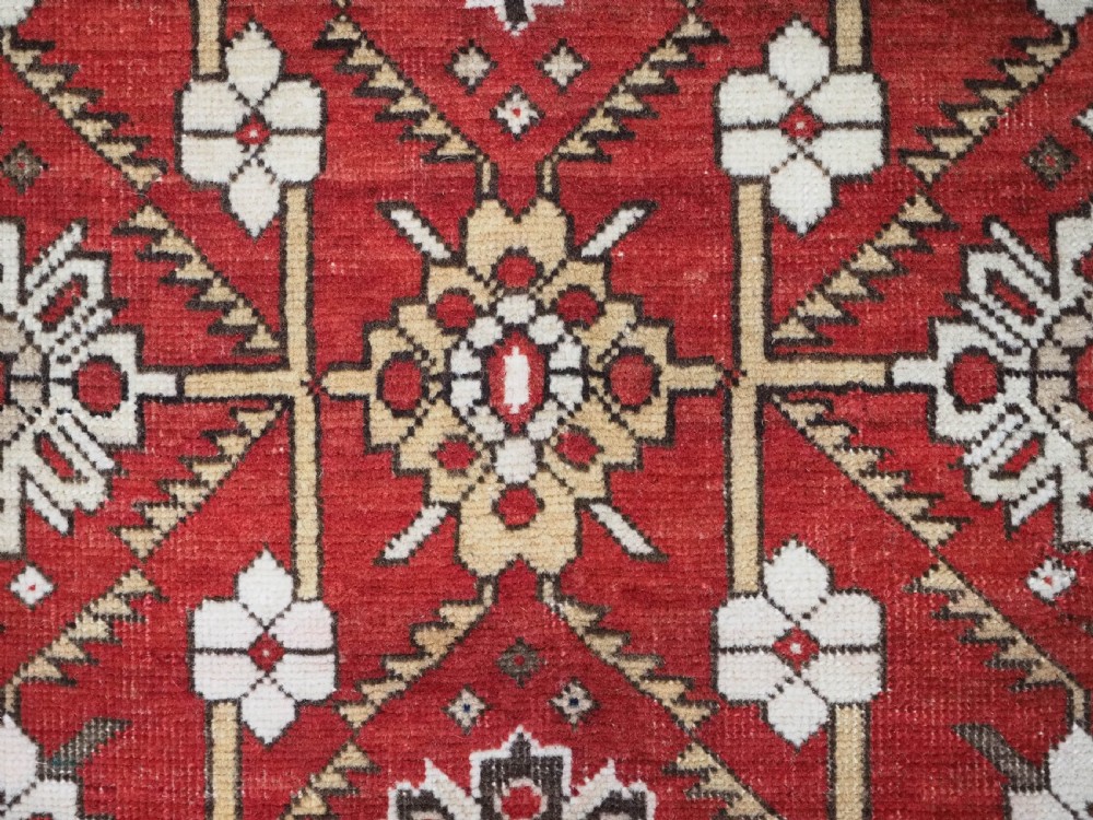 An antique hand-knotted Shirvan wool rug featuring a red field with an intricate cream floral lattice pattern framed by multi-layered geometric borders. View X