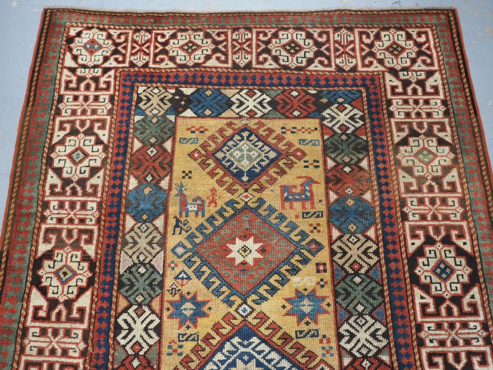 An antique South Caucasian hand-knotted wool rug with a vibrant yellow central field, diamond medallions, and ornate multi-coloured geometric borders. View III