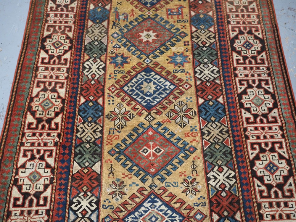 An antique South Caucasian hand-knotted wool rug with a vibrant yellow central field, diamond medallions, and ornate multi-coloured geometric borders. View IV