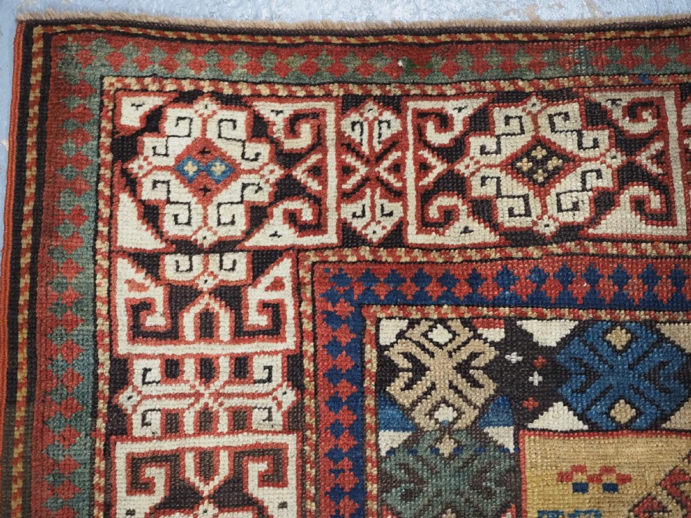 An antique South Caucasian hand-knotted wool rug with a vibrant yellow central field, diamond medallions, and ornate multi-coloured geometric borders. View VII