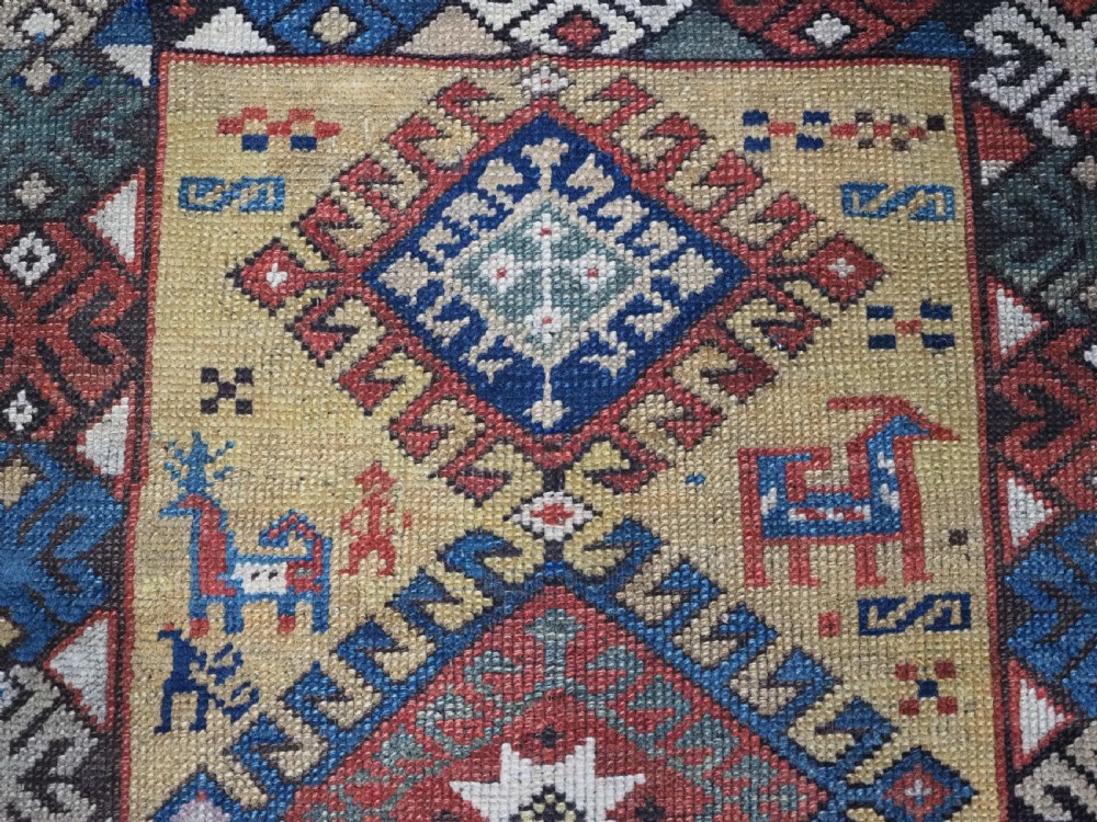 An antique South Caucasian hand-knotted wool rug with a vibrant yellow central field, diamond medallions, and ornate multi-coloured geometric borders. View IX