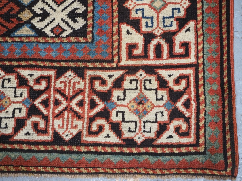 An antique South Caucasian hand-knotted wool rug with a vibrant yellow central field, diamond medallions, and ornate multi-coloured geometric borders. View XII