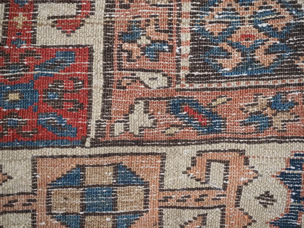 An antique Kurdish wool runner rug featuring a dark central field filled with diamond latch hook medallions and geometric polychrome borders. View XIV