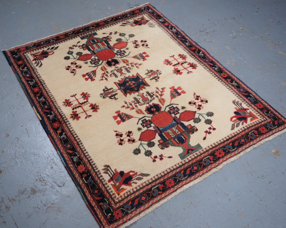 A hand-woven antique Afshar wool rug featuring geometric vase motifs in red, navy, and green on an ivory field with a dark border. View II