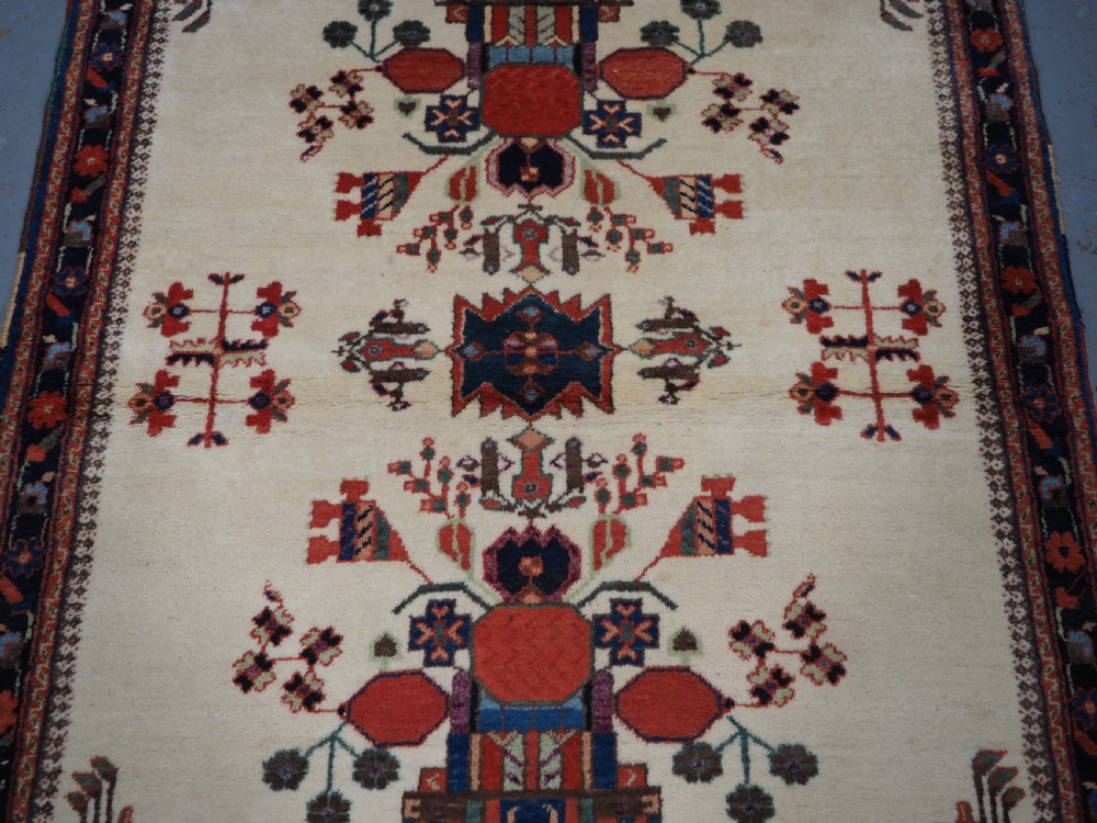 A hand-woven antique Afshar wool rug featuring geometric vase motifs in red, navy, and green on an ivory field with a dark border. View IV