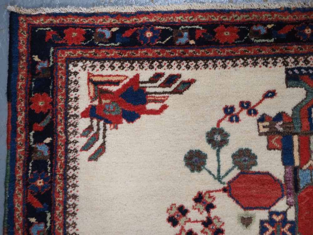 A hand-woven antique Afshar wool rug featuring geometric vase motifs in red, navy, and green on an ivory field with a dark border. View VI