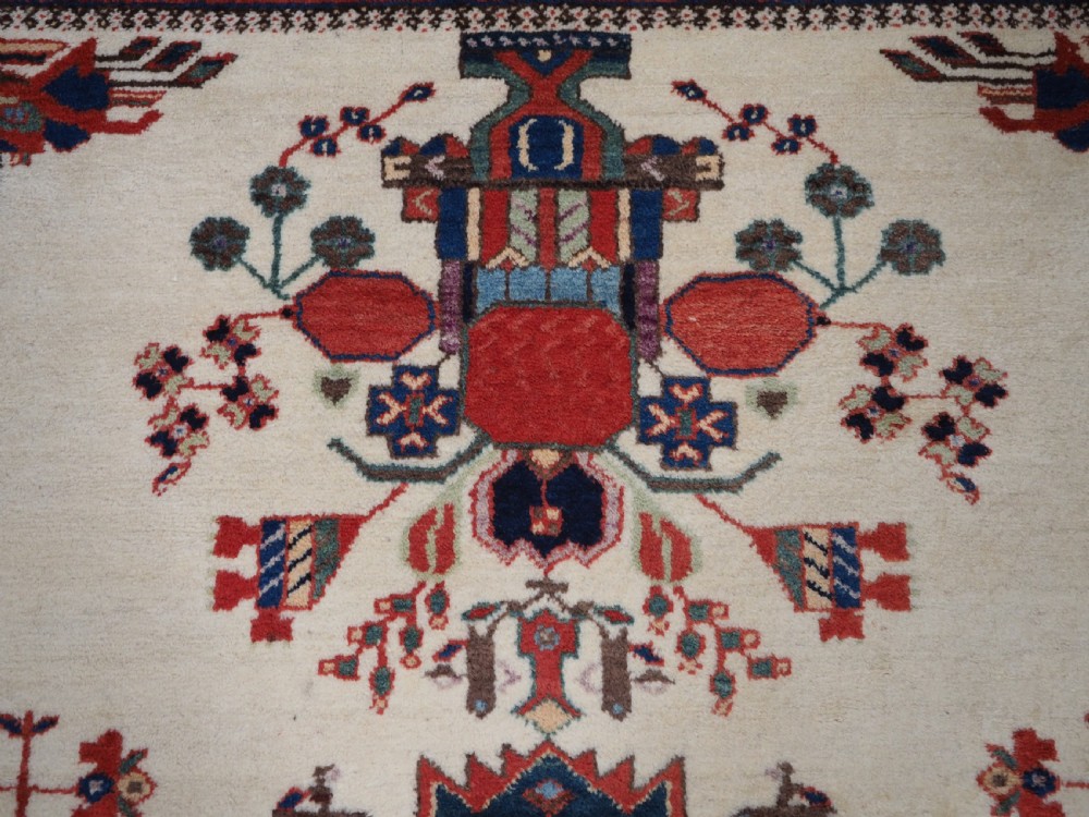 A hand-woven antique Afshar wool rug featuring geometric vase motifs in red, navy, and green on an ivory field with a dark border. View VII