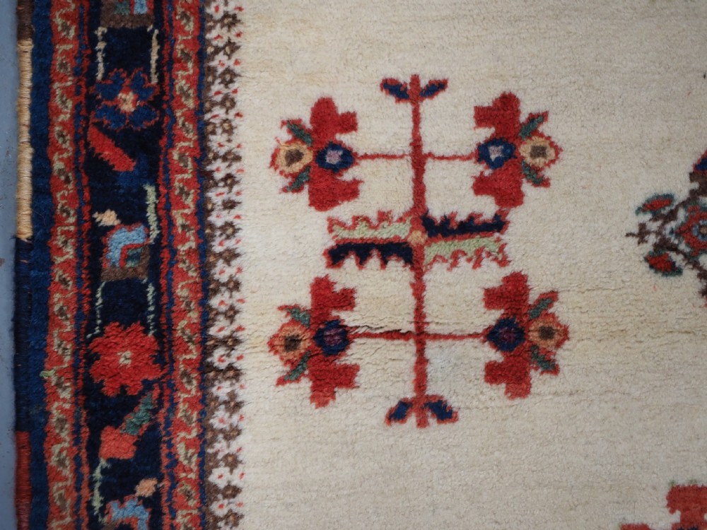 A hand-woven antique Afshar wool rug featuring geometric vase motifs in red, navy, and green on an ivory field with a dark border. View VIII