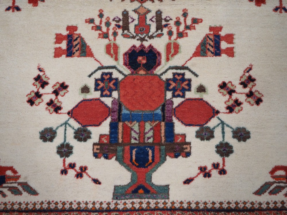 A hand-woven antique Afshar wool rug featuring geometric vase motifs in red, navy, and green on an ivory field with a dark border. View XII