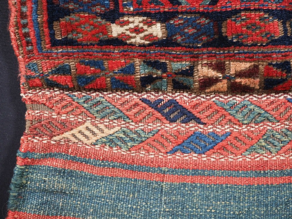 An antique Kurdish Jaf tribal bag featuring a hand-knotted diamond geometric pattern on the front and a striped plain weave backing in red, blue, and teal shades. View IV