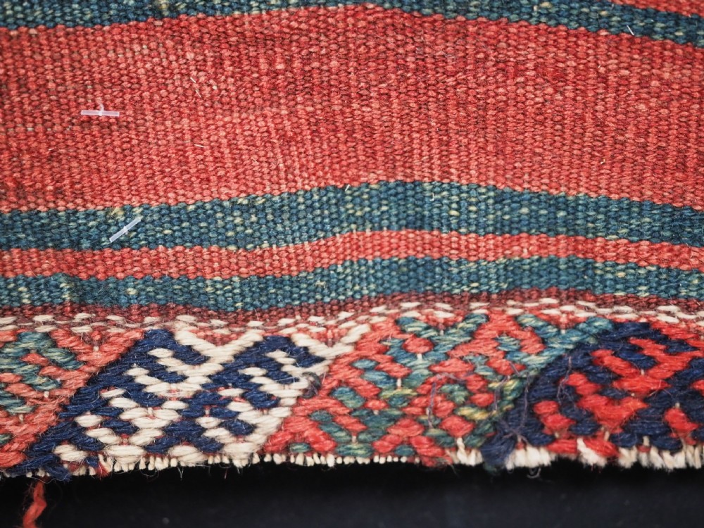 An antique Kurdish Jaf tribal bag featuring a hand-knotted diamond geometric pattern on the front and a striped plain weave backing in red, blue, and teal shades. View IX