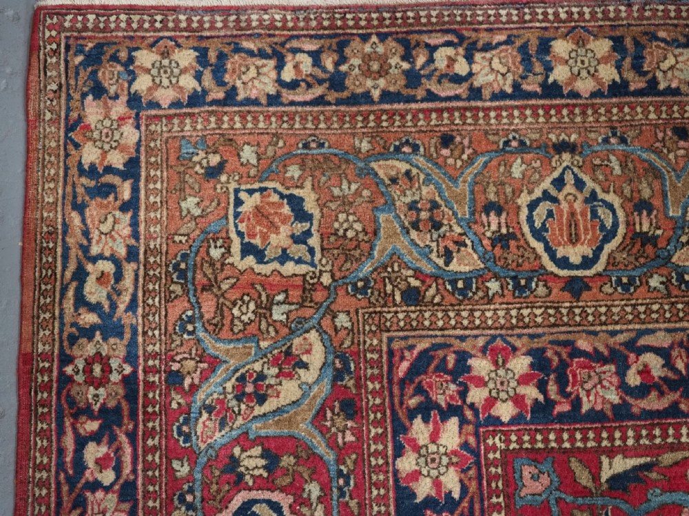 An antique rectangular Isfahan carpet featuring a detailed central medallion, cream field with red and blue floral arabesques, and a decorative multi-banded border. View VI