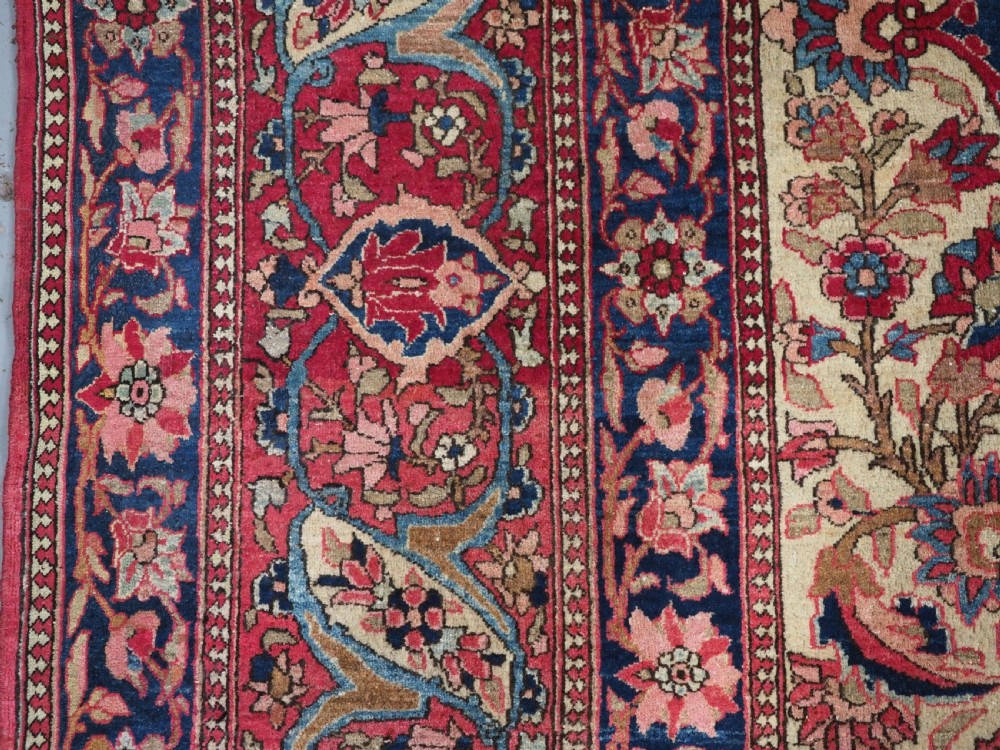 An antique rectangular Isfahan carpet featuring a detailed central medallion, cream field with red and blue floral arabesques, and a decorative multi-banded border. View VII
