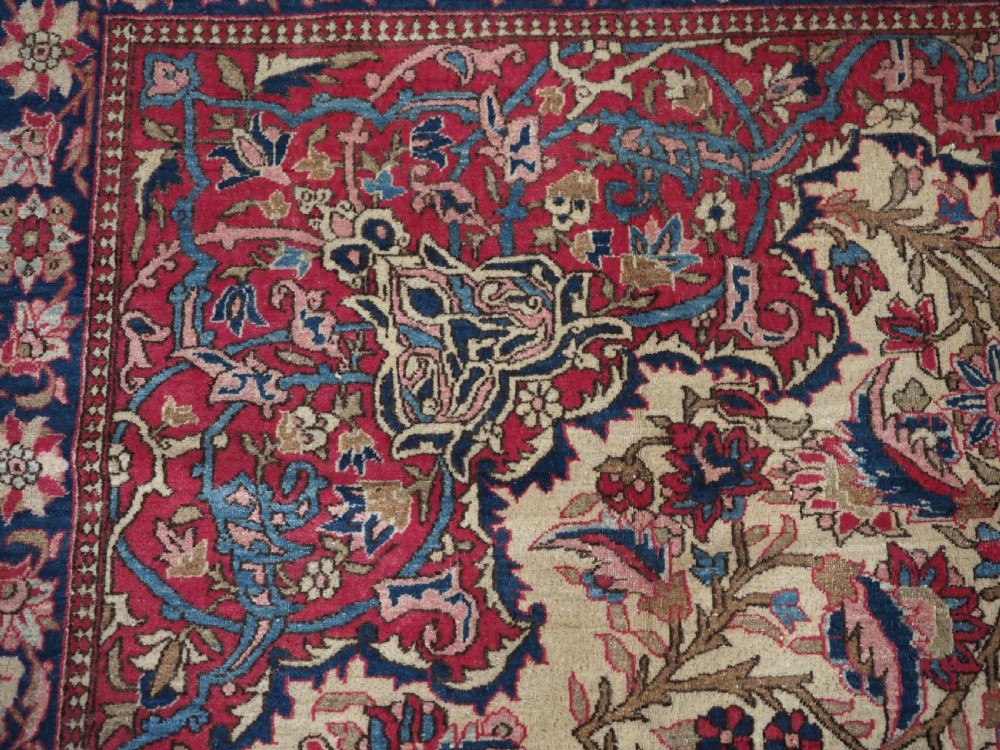 An antique rectangular Isfahan carpet featuring a detailed central medallion, cream field with red and blue floral arabesques, and a decorative multi-banded border. View VIII