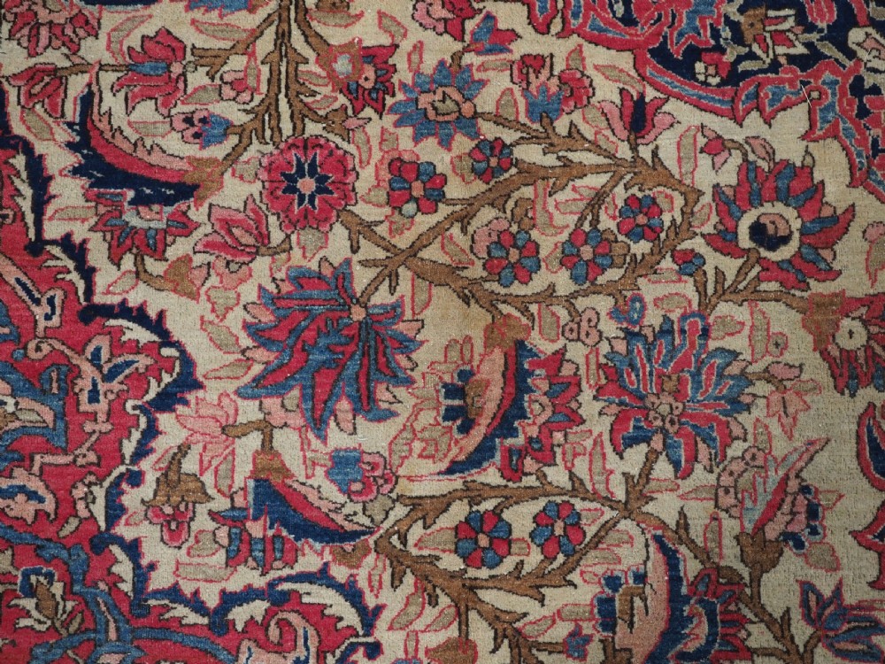 An antique rectangular Isfahan carpet featuring a detailed central medallion, cream field with red and blue floral arabesques, and a decorative multi-banded border. View XIII