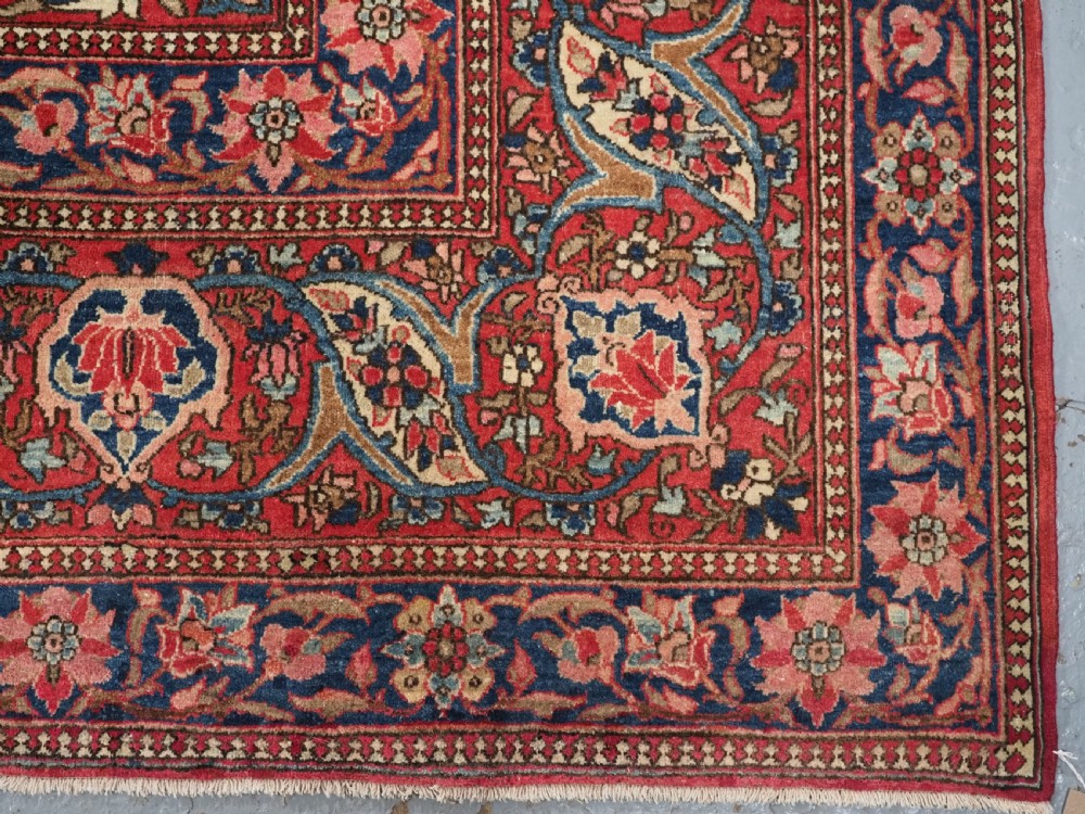 An antique rectangular Isfahan carpet featuring a detailed central medallion, cream field with red and blue floral arabesques, and a decorative multi-banded border. View XVI