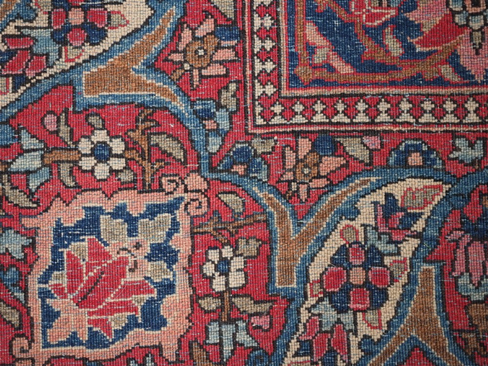 An antique rectangular Isfahan carpet featuring a detailed central medallion, cream field with red and blue floral arabesques, and a decorative multi-banded border. View XVII
