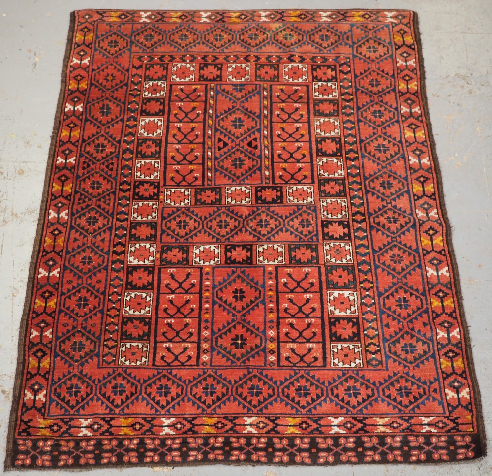 An antique rectangular hand-knotted wool Ersari Turkmen ensi rug featuring a four-panel hatchli pattern in terracotta red, dark blue, and ivory geometric motifs.