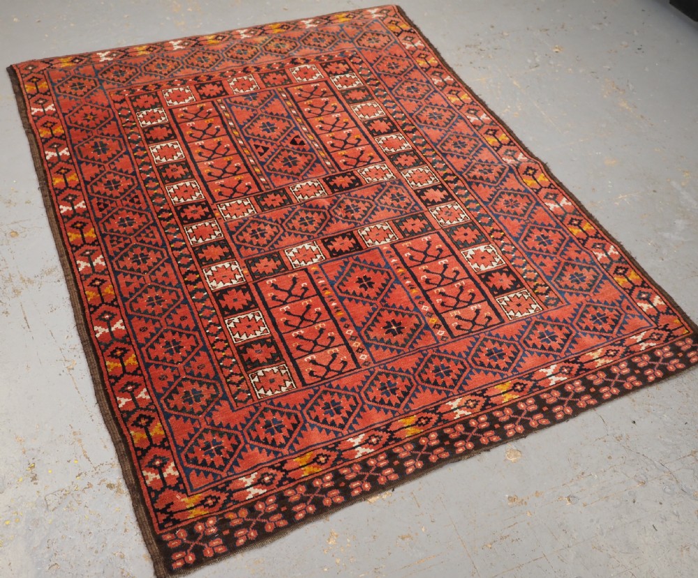 An antique rectangular hand-knotted wool Ersari Turkmen ensi rug featuring a four-panel hatchli pattern in terracotta red, dark blue, and ivory geometric motifs. View II