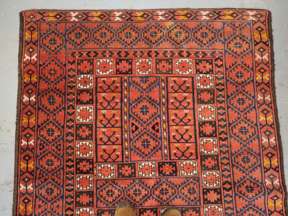 An antique rectangular hand-knotted wool Ersari Turkmen ensi rug featuring a four-panel hatchli pattern in terracotta red, dark blue, and ivory geometric motifs. View III