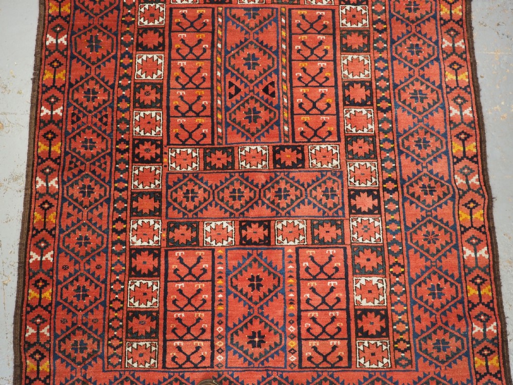 An antique rectangular hand-knotted wool Ersari Turkmen ensi rug featuring a four-panel hatchli pattern in terracotta red, dark blue, and ivory geometric motifs. View IV