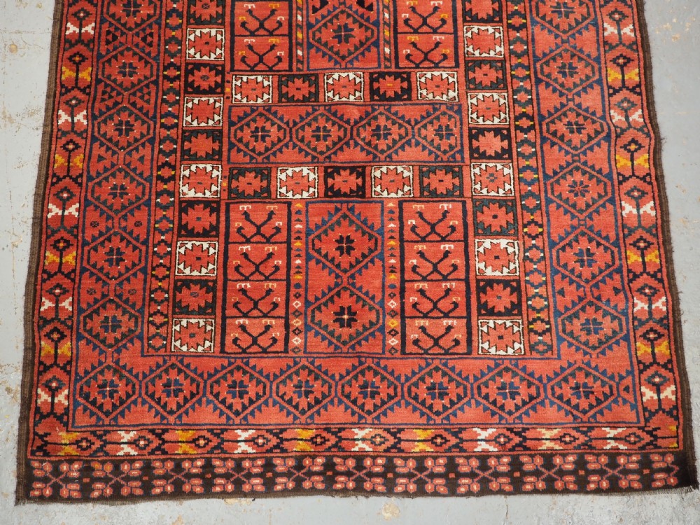 An antique rectangular hand-knotted wool Ersari Turkmen ensi rug featuring a four-panel hatchli pattern in terracotta red, dark blue, and ivory geometric motifs. View V