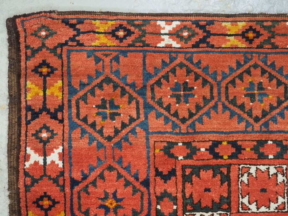 An antique rectangular hand-knotted wool Ersari Turkmen ensi rug featuring a four-panel hatchli pattern in terracotta red, dark blue, and ivory geometric motifs. View VI