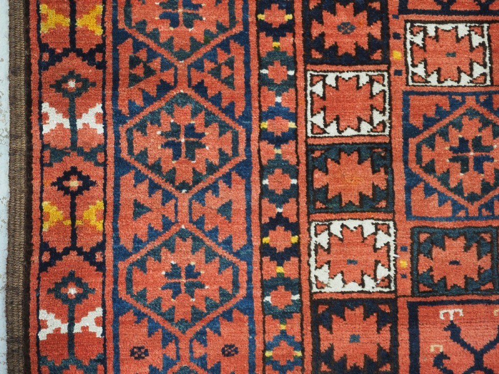 An antique rectangular hand-knotted wool Ersari Turkmen ensi rug featuring a four-panel hatchli pattern in terracotta red, dark blue, and ivory geometric motifs. View VII