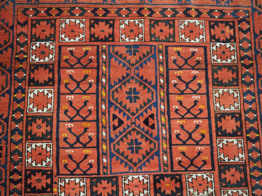 An antique rectangular hand-knotted wool Ersari Turkmen ensi rug featuring a four-panel hatchli pattern in terracotta red, dark blue, and ivory geometric motifs. View VIII