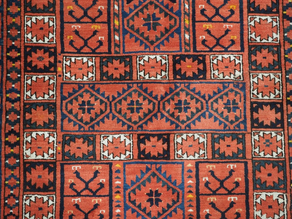 An antique rectangular hand-knotted wool Ersari Turkmen ensi rug featuring a four-panel hatchli pattern in terracotta red, dark blue, and ivory geometric motifs. View IX