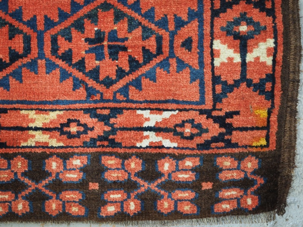 An antique rectangular hand-knotted wool Ersari Turkmen ensi rug featuring a four-panel hatchli pattern in terracotta red, dark blue, and ivory geometric motifs. View XIV