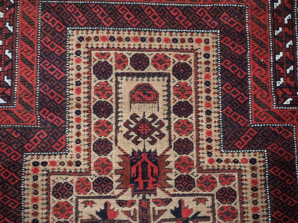 An antique Baluch wool prayer rug featuring a central mihrab arch, tree motifs, hand icons, and geometric borders in dark red, brown, and camel shades. View VIII